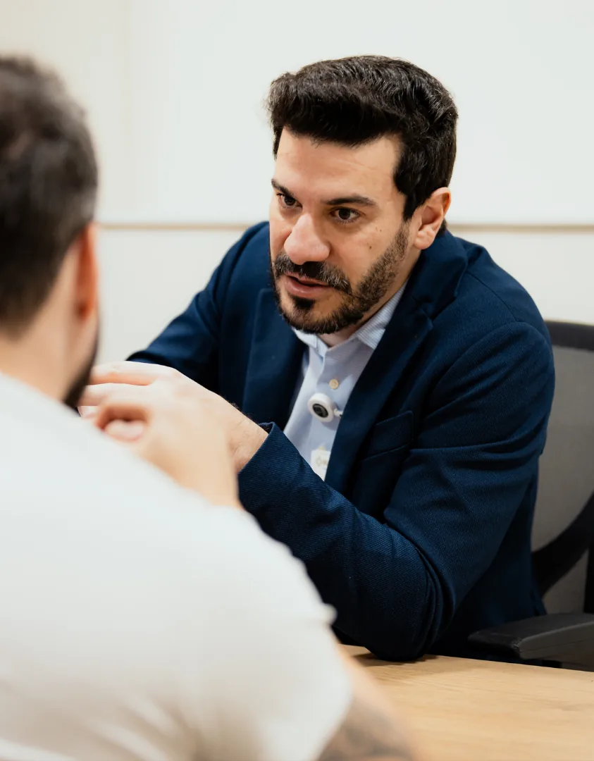 Dr. Henrique Cembranelli em consulta, conversando com paciente sobre tratamento da mão