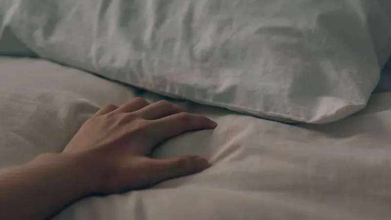 Mão apoiada sobre o lençol da cama pela manhã, cena das pontas dos dedos dormentes ao acordar